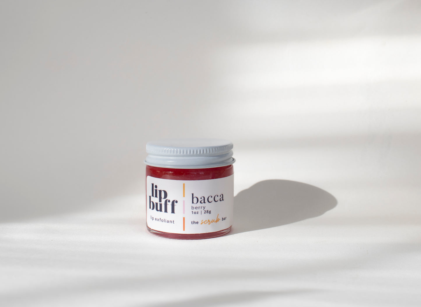 A close-up of The Scrub Bar's handmade berry-scented exfoliating lip scrub in a glass jar. The lip scrub helps exfoliate lips, making them smooth and kissable. Perfect for treating your lips to a gentle scrub and revealing softer skin.
