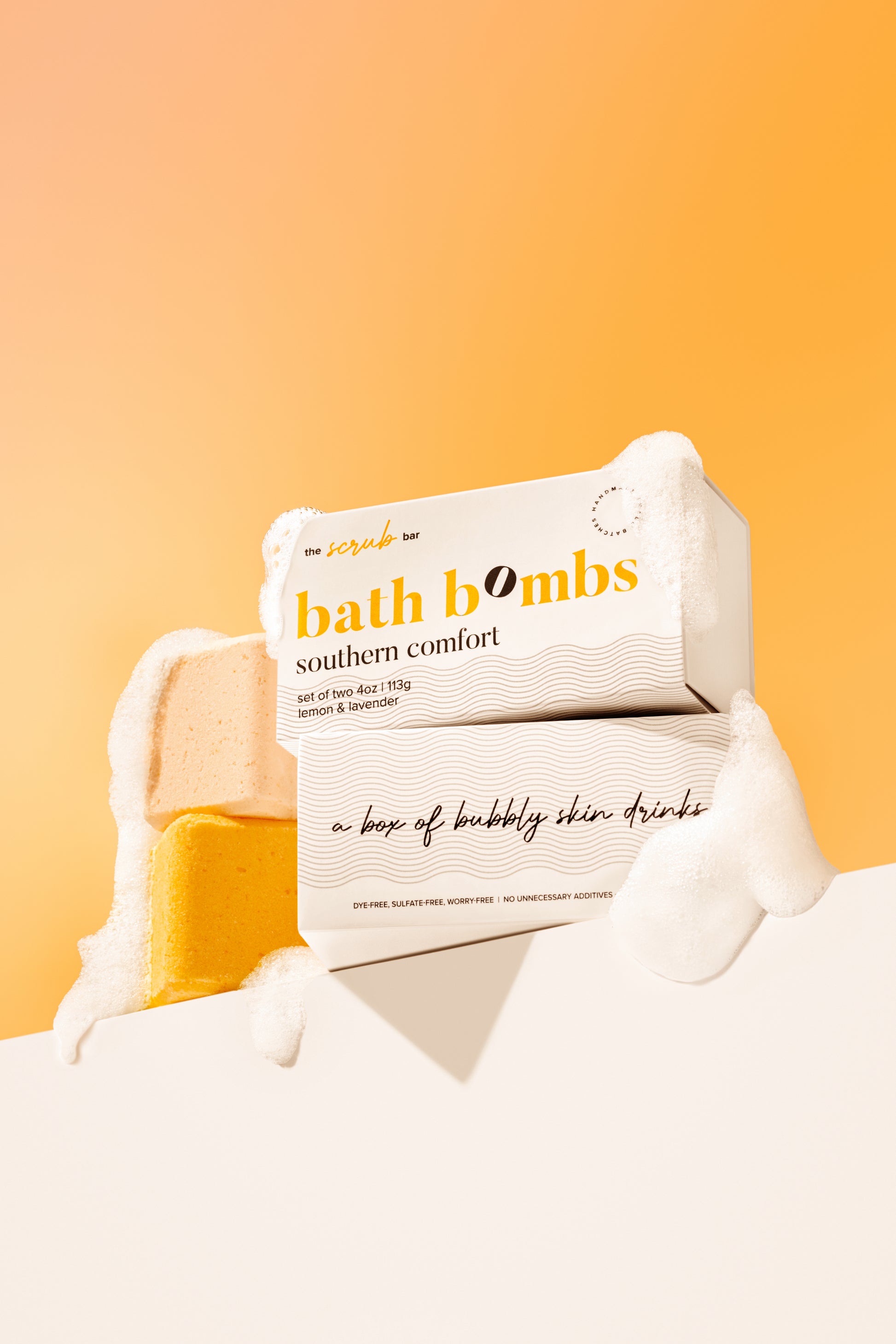 The Scrub Bar's Southern Comfort bath bomb box set with soft bubbles and  with its lavender and lemon bombs partially exposed. 