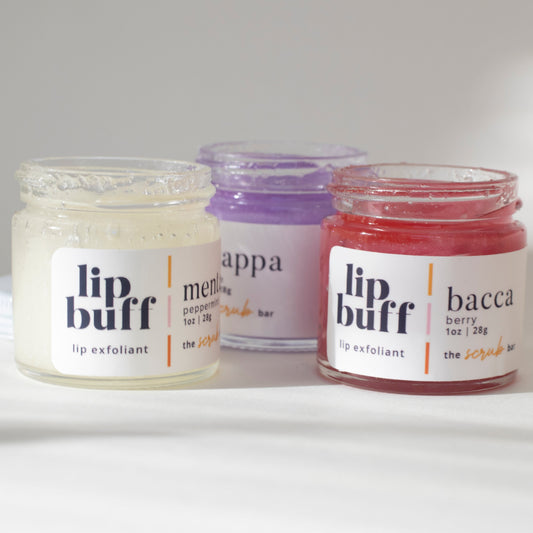 A trio of exfoliating lip scrubs from The Scrub Bar, including peppermint, grape, and berry. These handmade lip scrubs are perfect for exfoliating lips, revealing smoother skin while moisturizing with natural ingredients. Essential for your skincare routine.